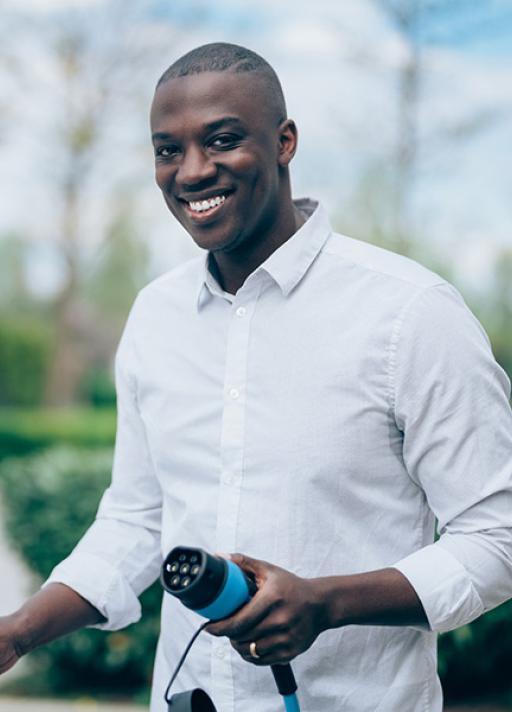 Un homme en chemise blanche et une recharge à la main sourit